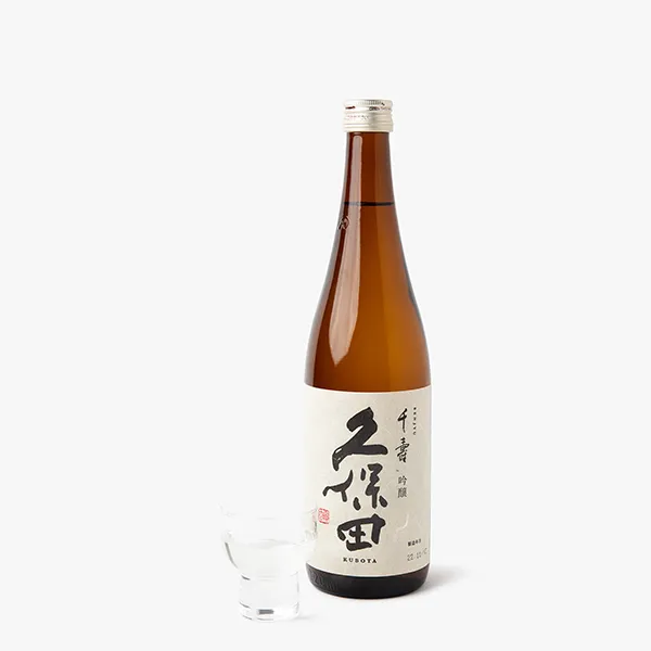 Bouteille de saké et petit verre sur fond blanc